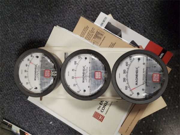 Analog pressure gauges used in blower door testing setup