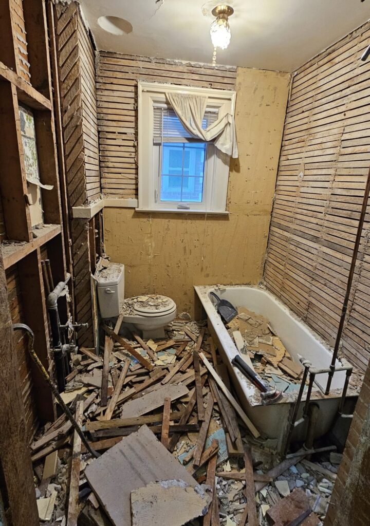 renovation in progress of a century-old bathroom with outdated plumbing and plaster walls