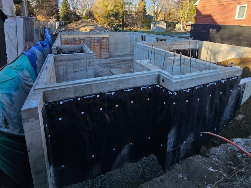 Dimple drainage board installed on exterior foundation wall to channel water away and protect dampproofing layer