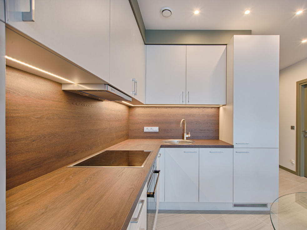A minimalist kitchen design featuring flat-panel cabinets, neutral colors, and clean, uncluttered surfaces