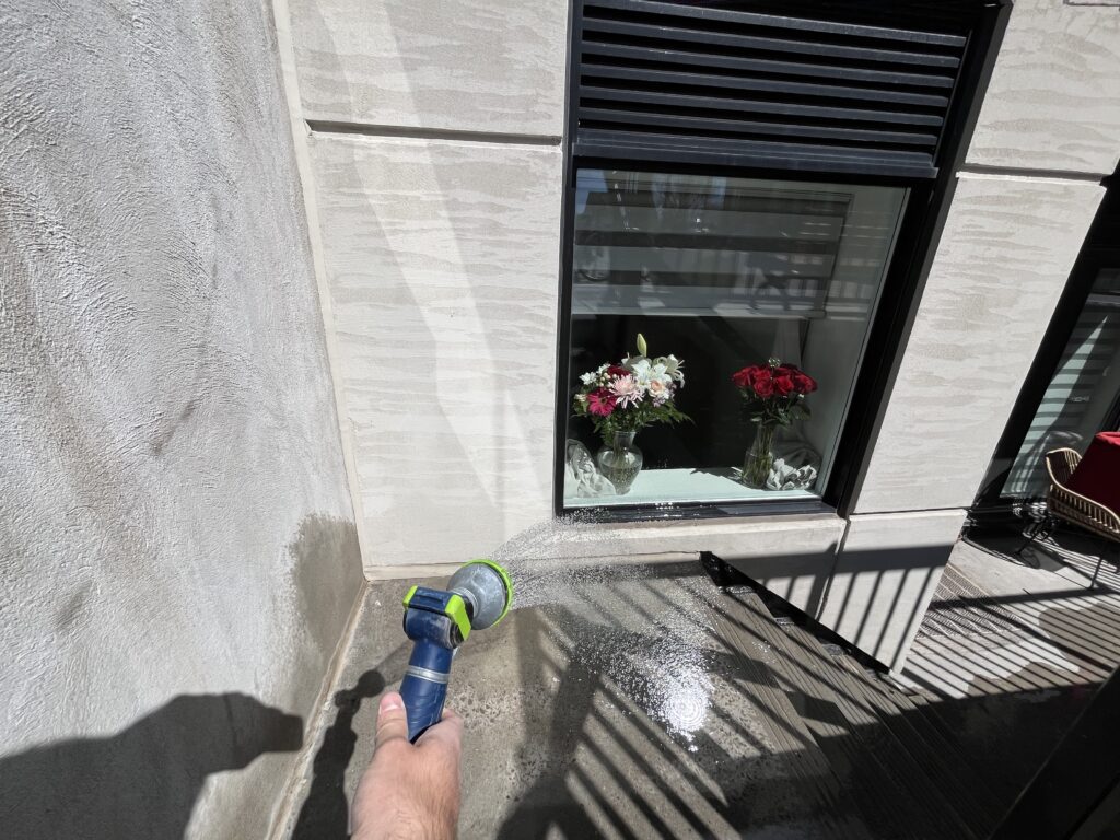 Spraying water on the exterior wall to simulate rain during blower door-assisted water leakage test