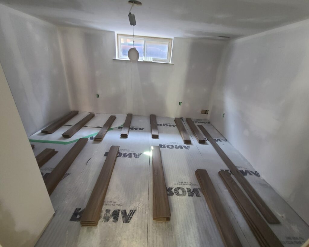 Vinyl plank flooring being installed over leveled concrete in a finished basement
