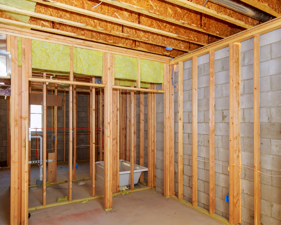 Basement framing with 2x4 wood studs installed along concrete foundation walls