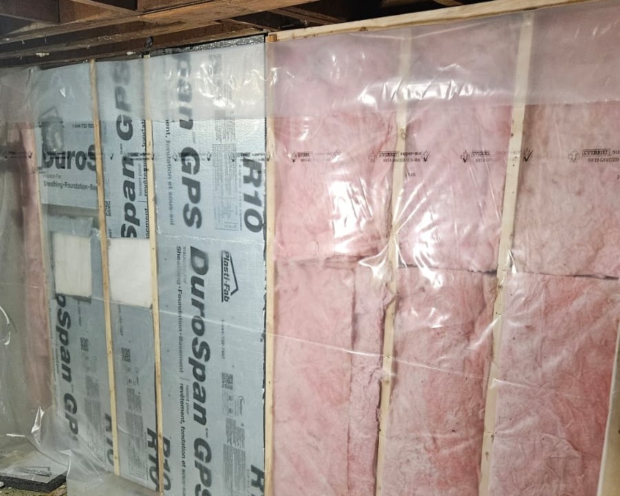 Fiberglass insulation and vapor barrier installed between studs on a basement wall