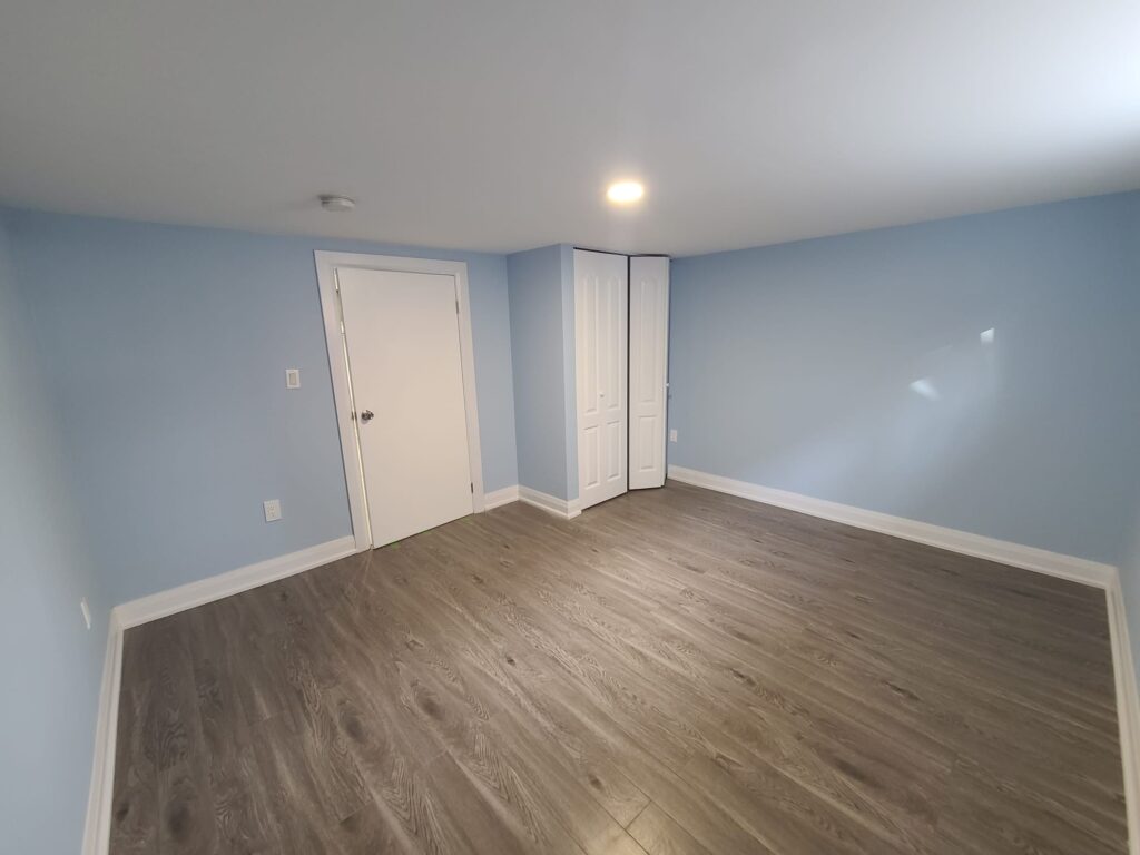 Painted basement walls with finished flooring in a completed basement renovation