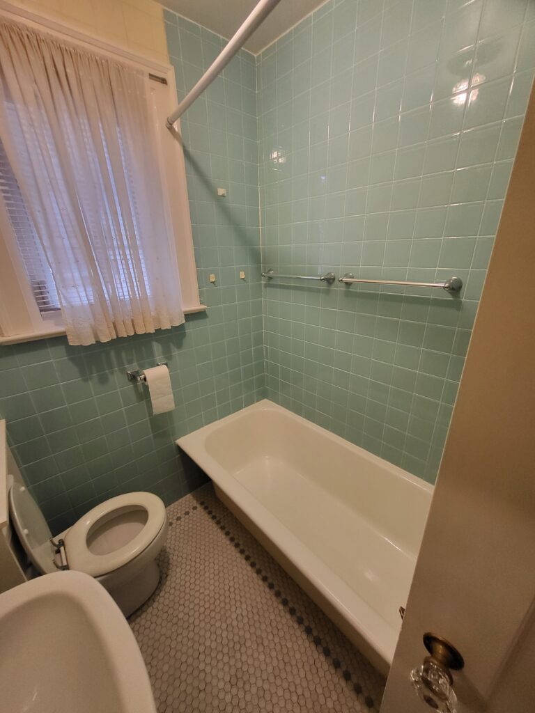Outdated bathroom in Midtown Toronto with pastel blue tiles and old bath tub before renovation by Olive Contractors