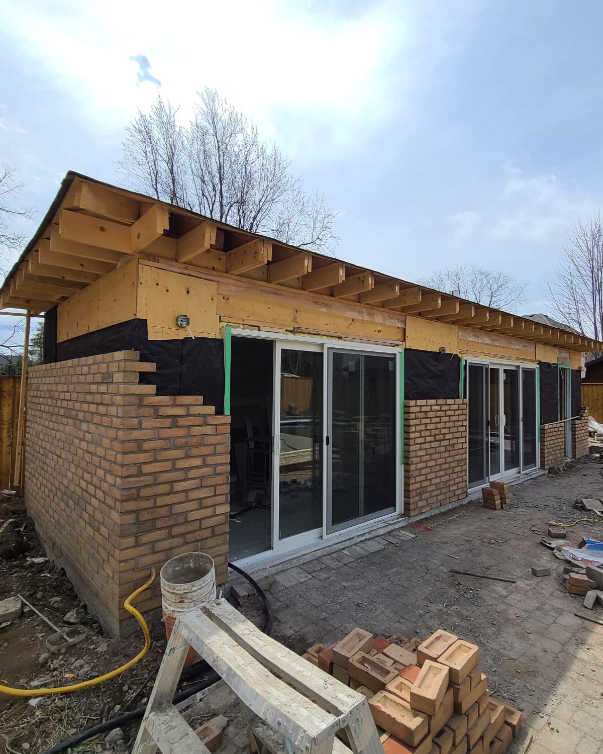 Exterior brick installation in progress on custom cabana house built in Central Ajax by Olive Contractors.