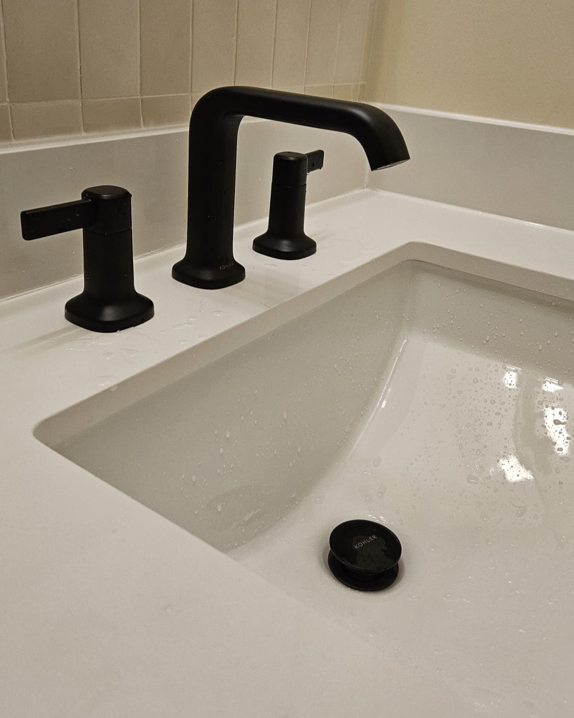 White quartz bathroom sink paired with a matte black single lever faucet, modern vanity detail in a contemporary bathroom renovation