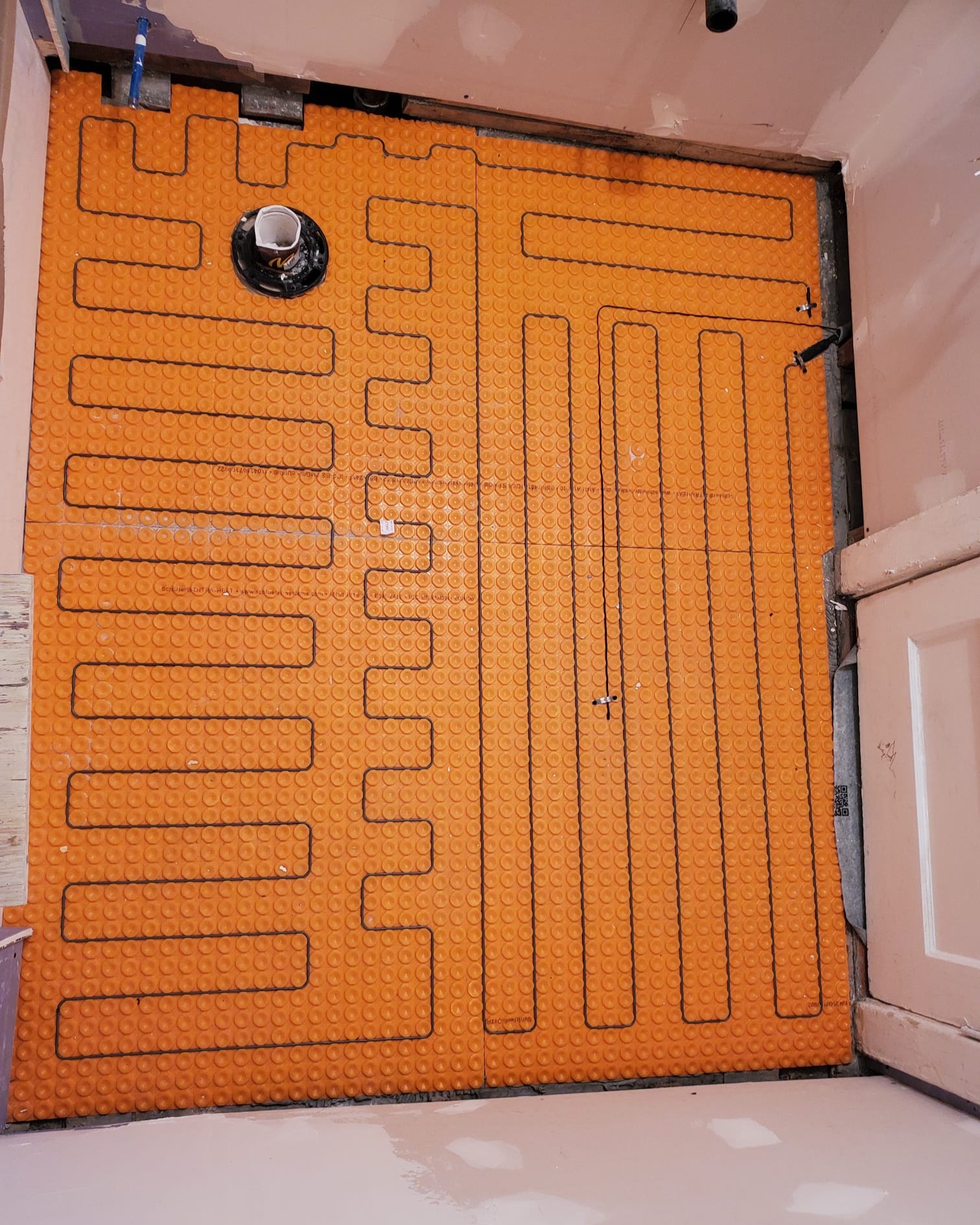 Close-up of Schluter membrane waterproofing system combined with in-floor heating system for durable and energy-efficient bathroom renovation.
