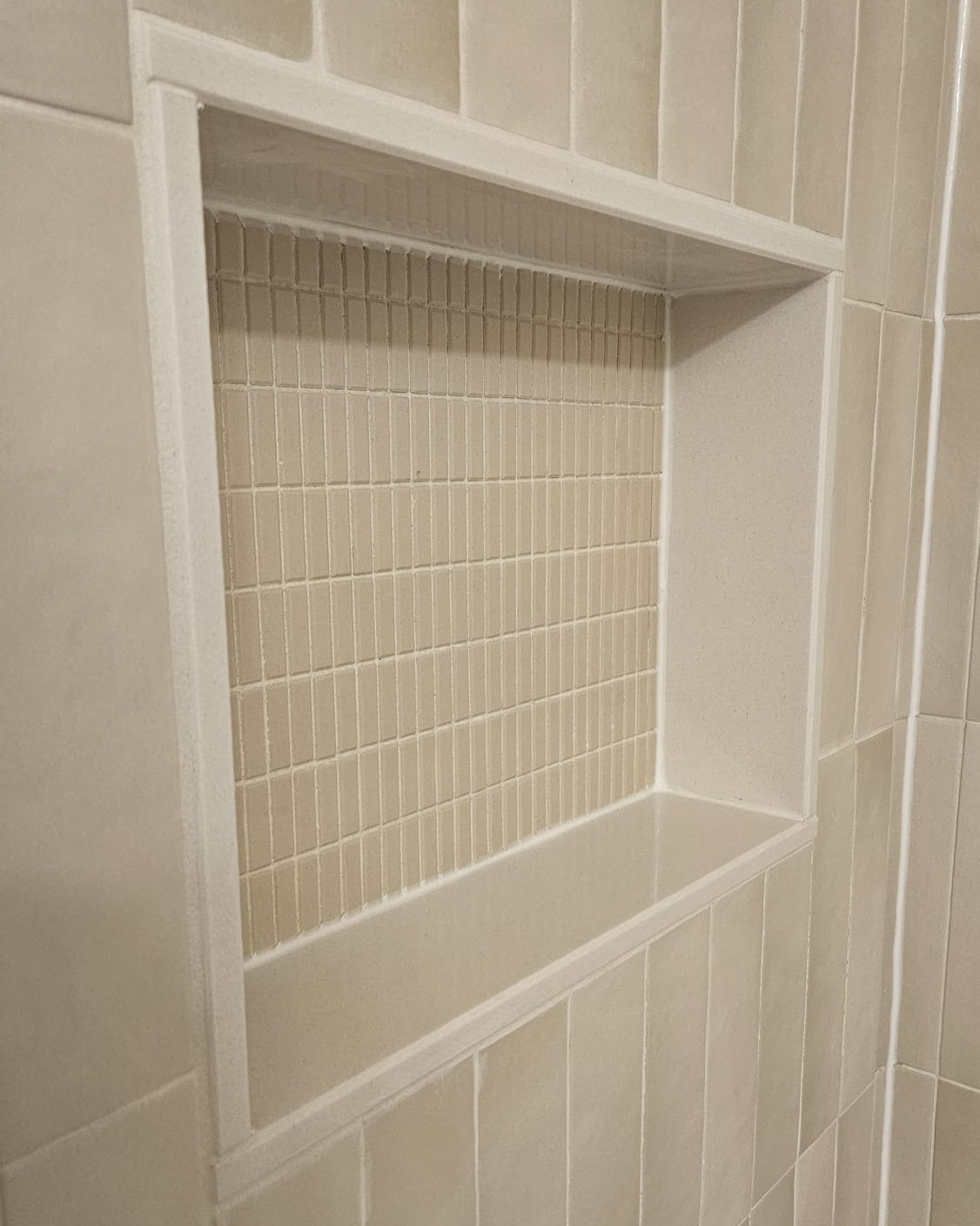 Close-up of a shower niche featuring real stone side panels and fine detailed craftsmanship in a modern bathroom renovation.