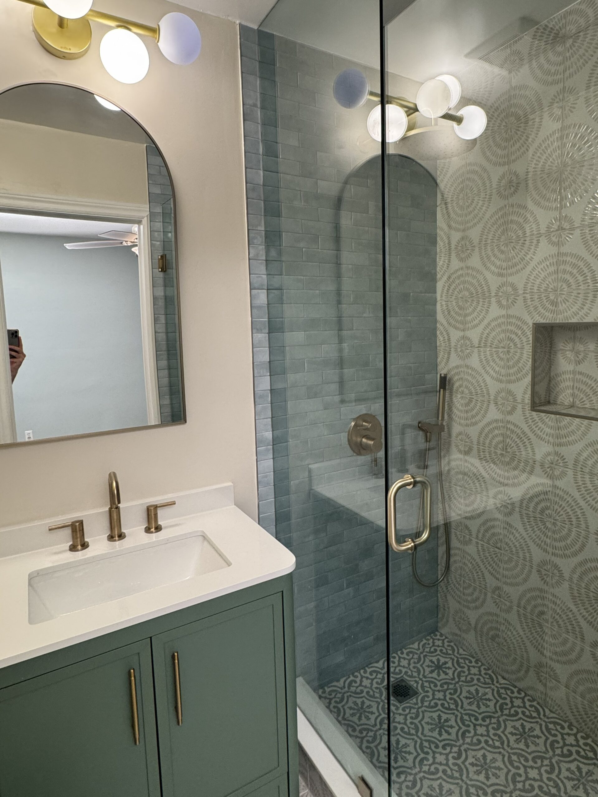 Completed ensuite bathroom renovation featuring green vanity, walk-in shower with patterned tiles, and brushed brass fixtures in Toronto hom
