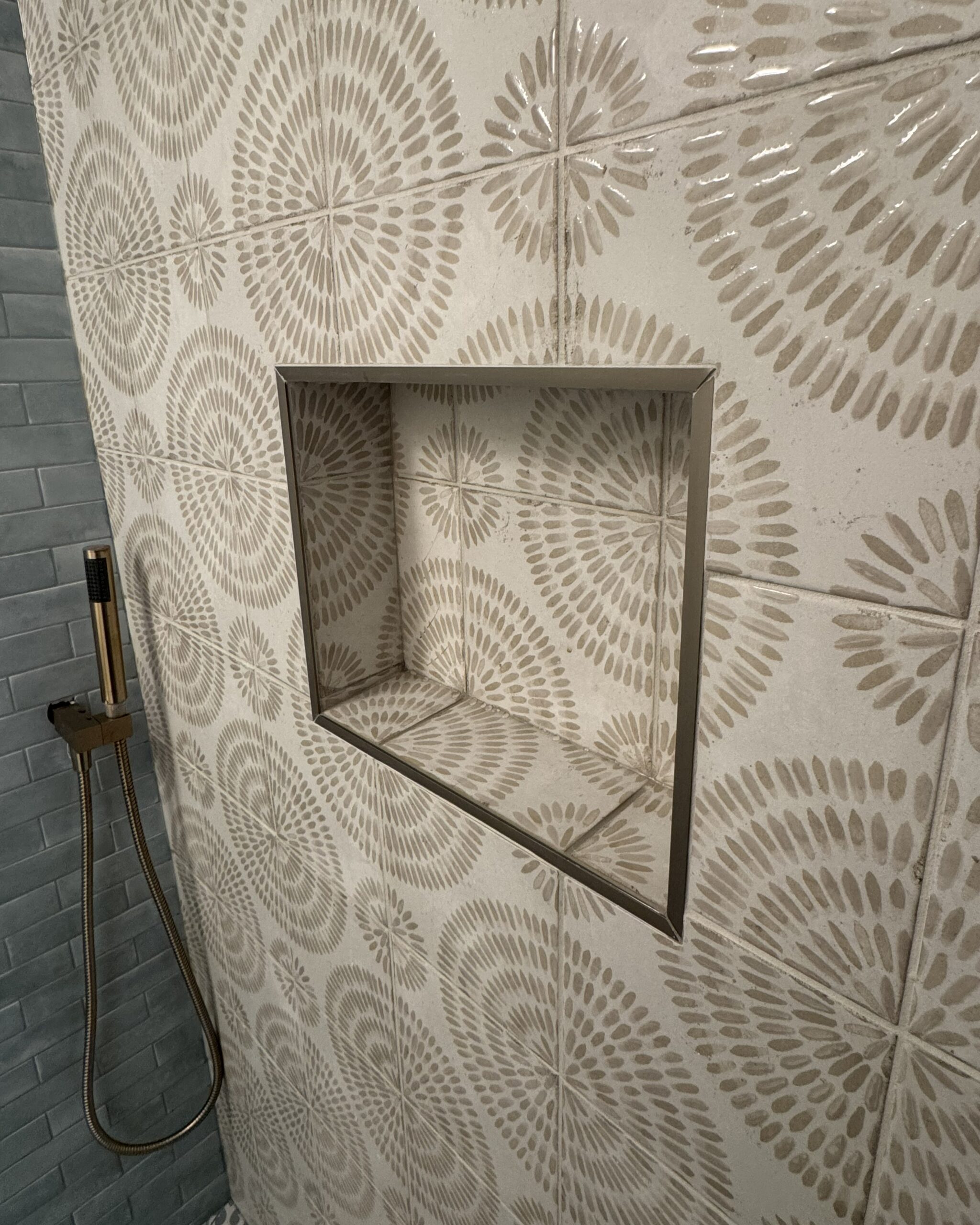 Built-in shower niche with brushed stainless steel trim and botanical wall tile in renovated ensuite bathroom Toronto