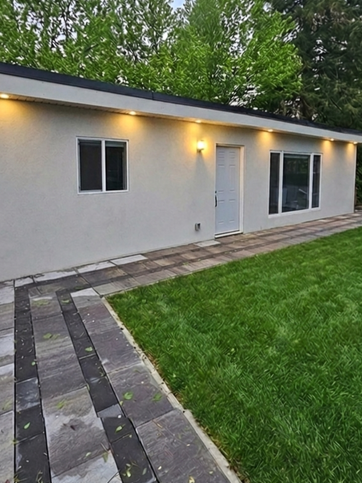 Backyard cabana rental unit with flat roof stucco exterior and stone paver walkway in Toronto