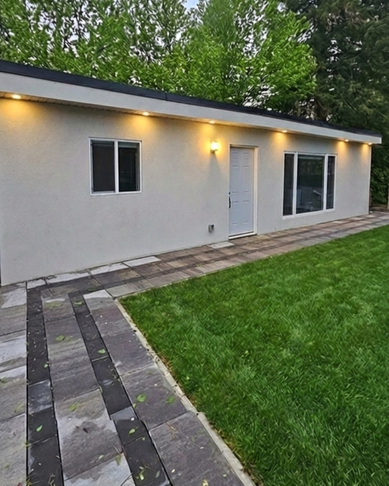 Backyard cabana rental unit with flat roof stucco exterior and stone paver walkway in Toronto