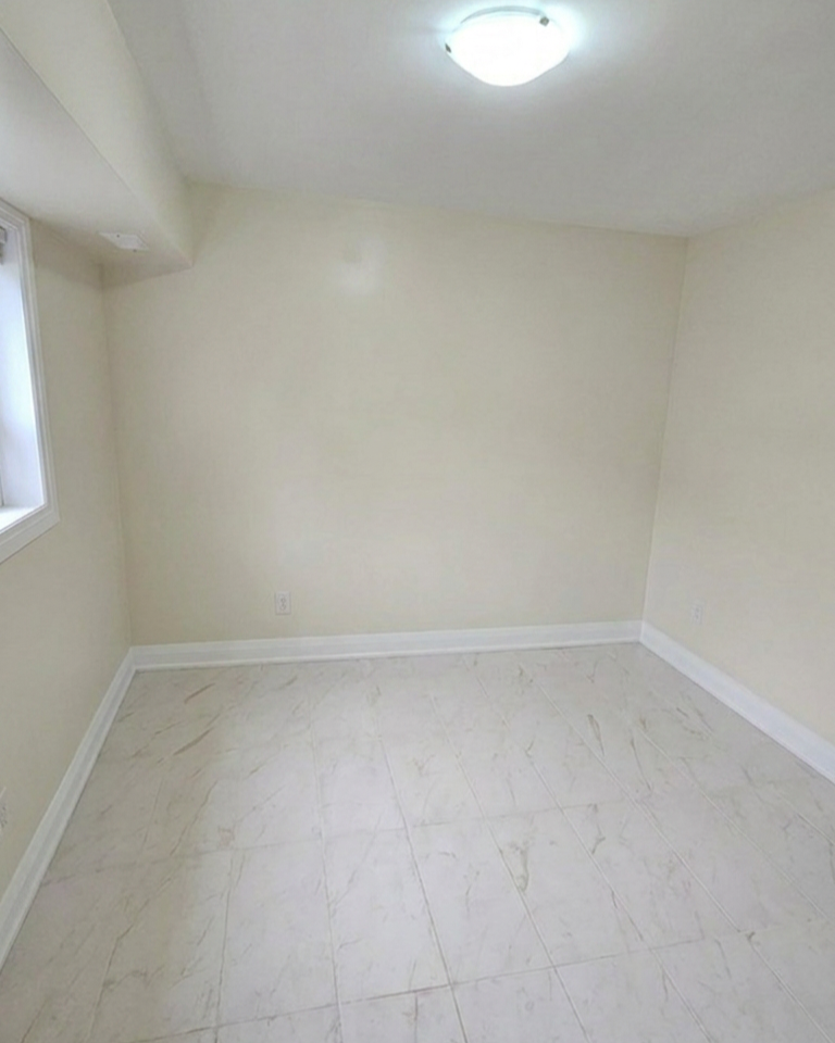 Finished bedroom with porcelain marble large-format floor tiles, and egress window