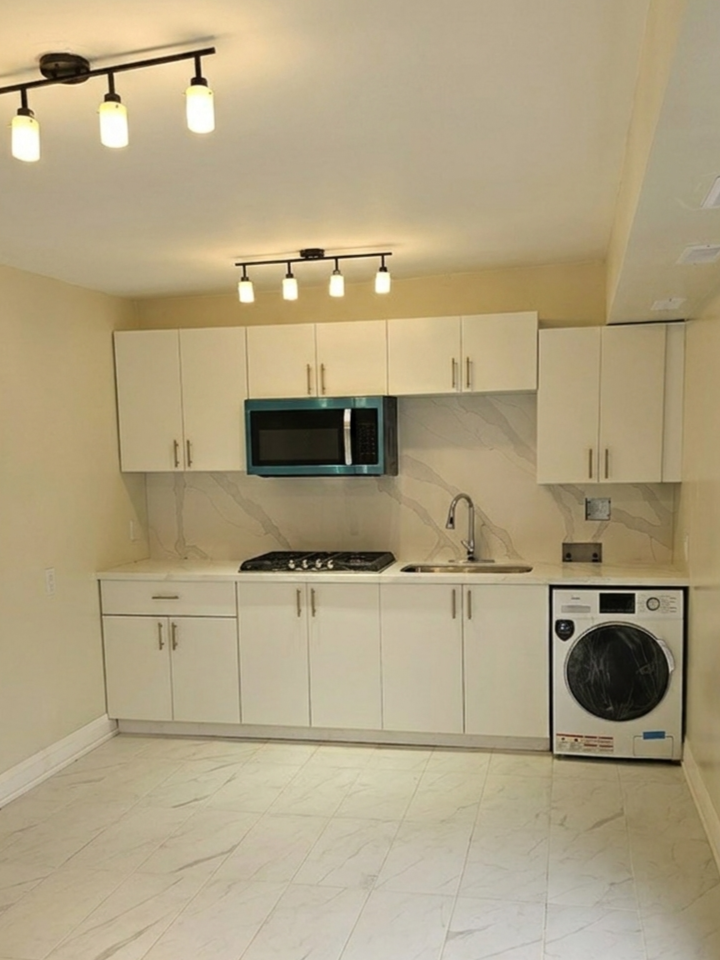 White shaker kitchen with quartz countertops and marble porcelain tile in a backyard cabana unit Toronto