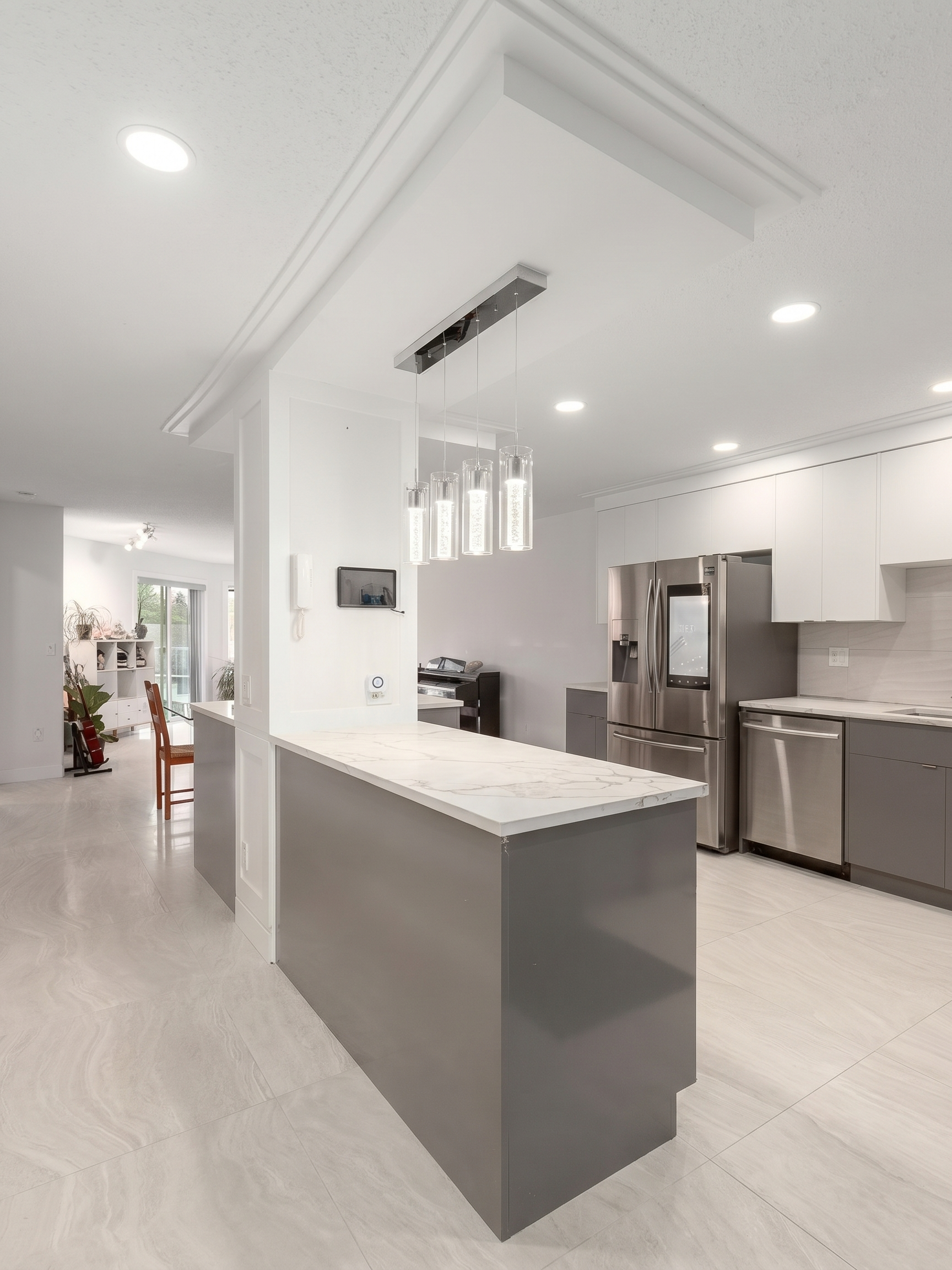 Renovated U-shaped kitchen with white upper cabinets, grey lower cabinets, and marble-look quartz waterfall island in North York