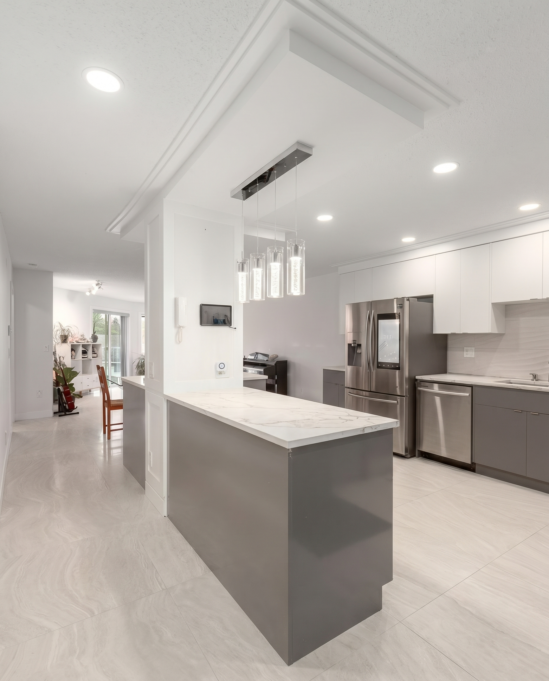 Renovated U-shaped kitchen with white upper cabinets, grey lower cabinets, and marble-look quartz waterfall island in North York