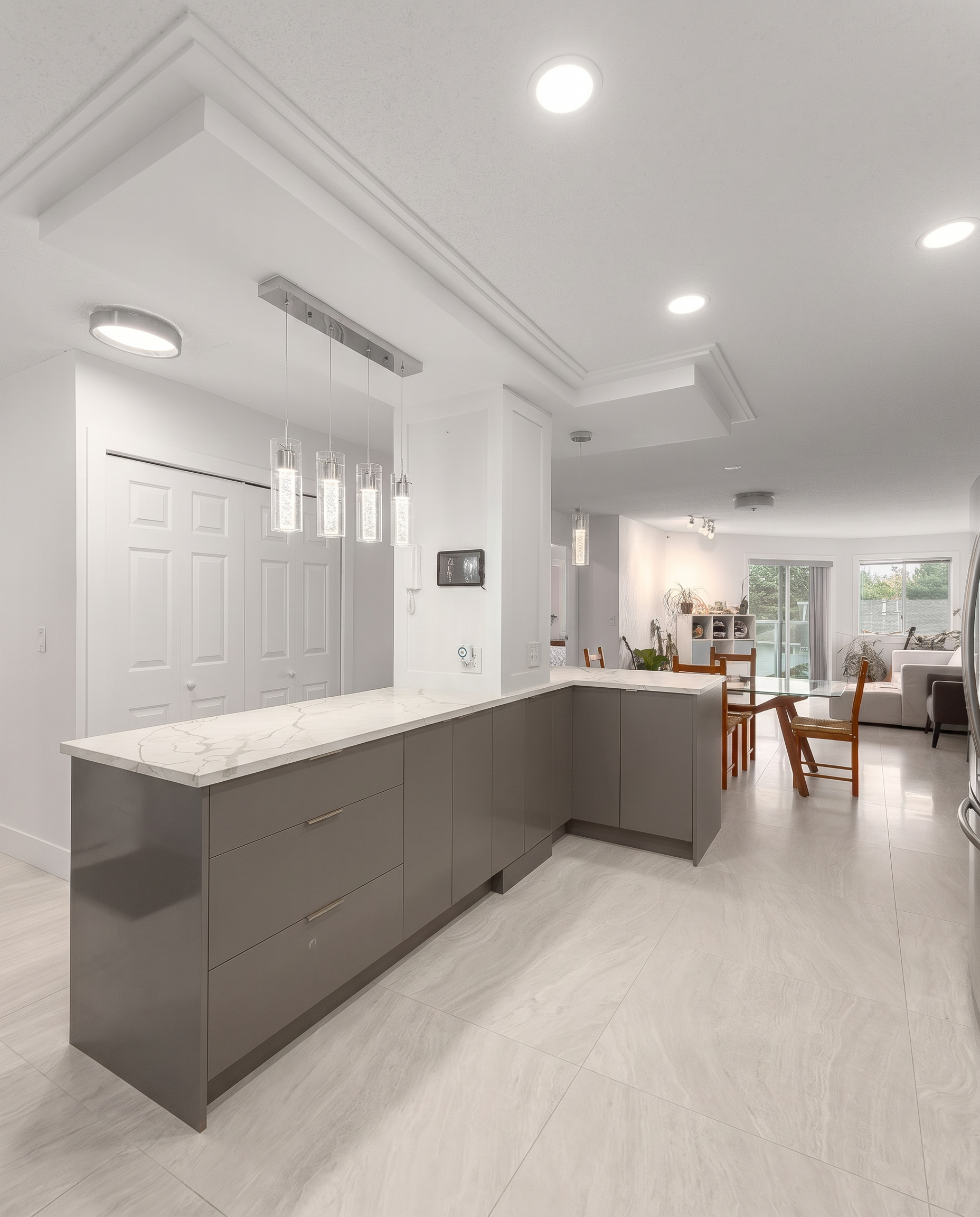 Open-concept kitchen peninsula with pendant lighting flowing into dining and living area in a renovated North York home
